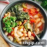 Hearty Italian Vegetable Soup 7 Minestrone soup recipe overhead in a blue bowl with kale and parsley on top.
