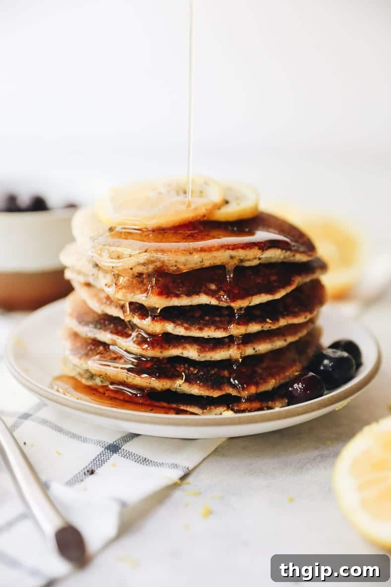 Bright Lemon Poppy Seed Pancakes 2 A stack of golden lemon poppyseed pancakes, garnished with lemon zest and fresh berries, ready for a healthy brunch.