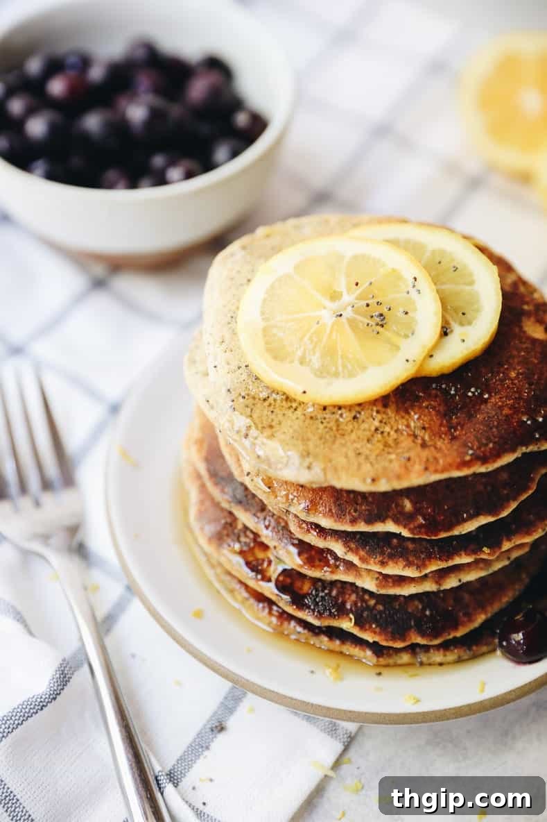 Bright Lemon Poppy Seed Pancakes 5 A beautifully styled flat lay of a stack of fluffy lemon poppyseed pancakes, topped with berries and maple syrup, ready to be enjoyed.