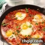 A top-down shot of a finished shakshuka in a cast iron skillet, garnished with fresh parsley and feta cheese, ready to be served.