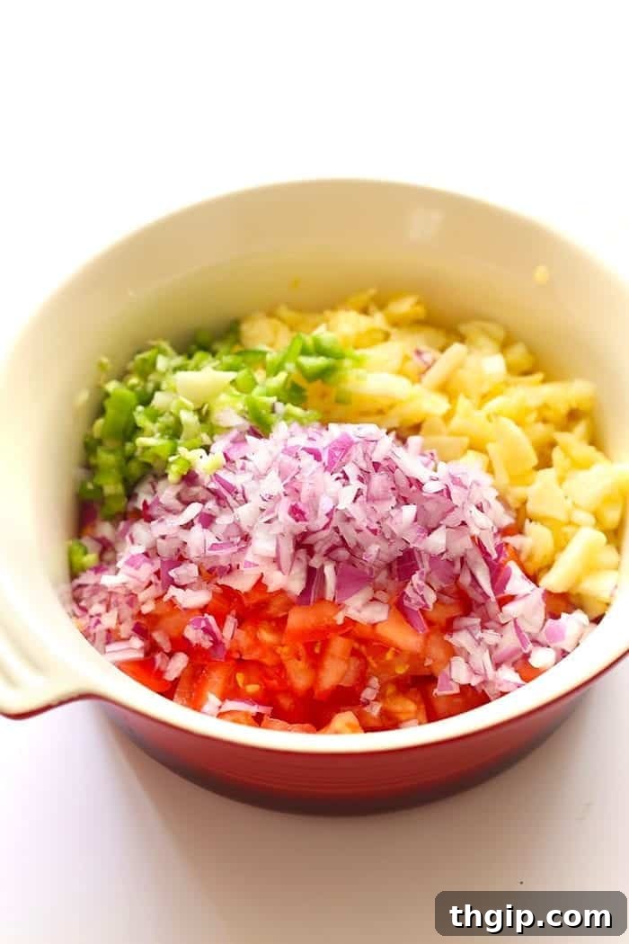 Close-up of freshly chopped ingredients including pineapple, tomatoes, red onion, and cilantro, ready to be mixed for pineapple salsa.