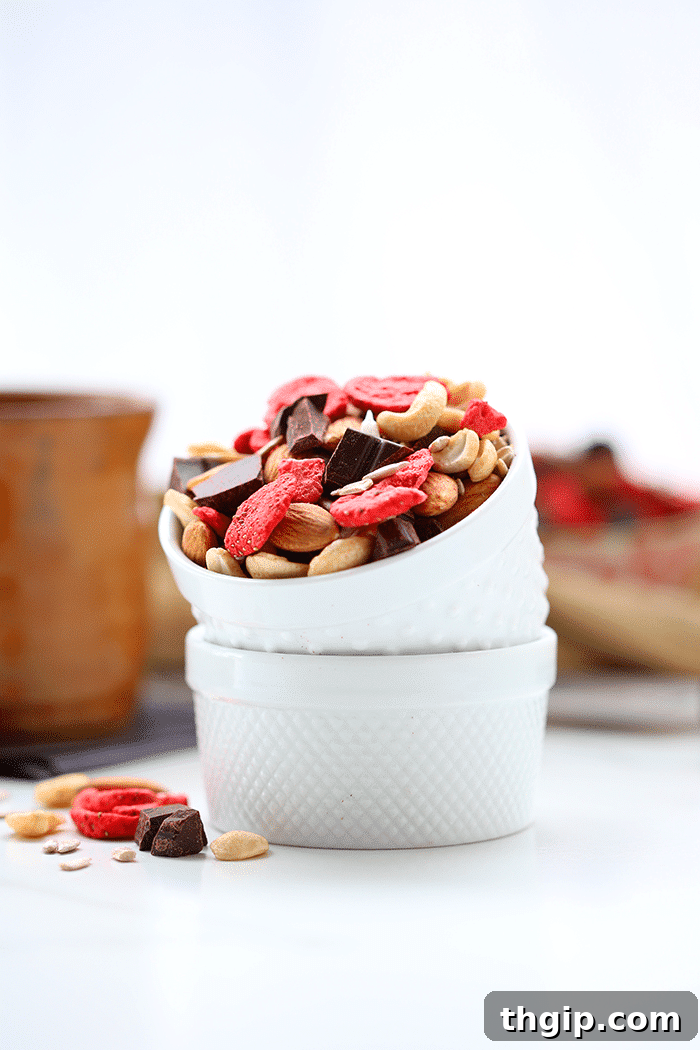 Crimson Cocoa Trail Mix 5 Two small bowls stacked and filled with trail mix made of mixed nuts, seeds, freeze dried strawberries and chocolate chunks.