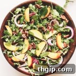 A vibrant Arugula Peach and Halloumi Salad with golden-brown halloumi cheese, sliced peaches, and fresh greens.