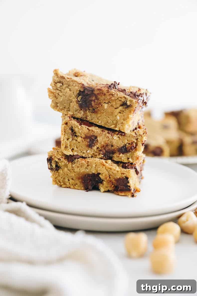 Wholesome Chickpea Blondies 2 Irresistible chickpea blondies stacked neatly on a small white plate, showcasing their fudgy texture and delicious chocolate chips.