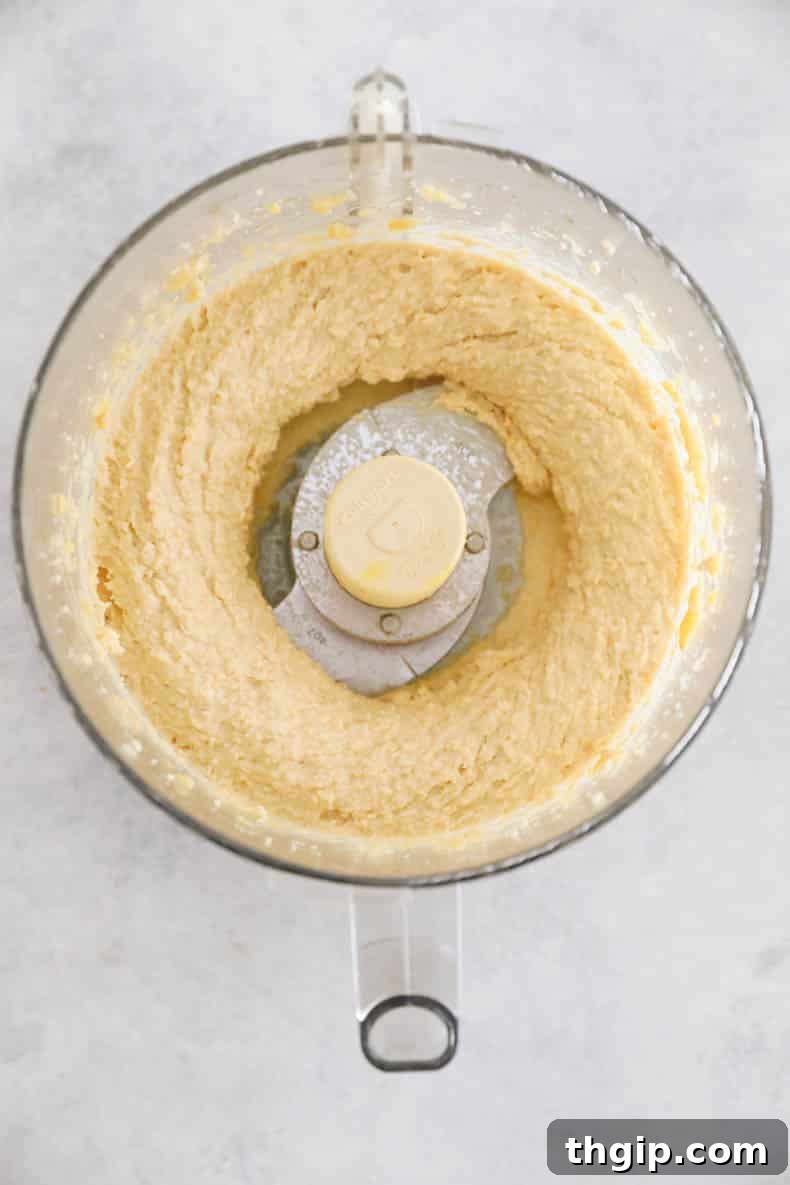 Wholesome Chickpea Blondies 4 Wet ingredients for chickpea blondies - chickpeas, nut butter, maple syrup, and vanilla - being processed in a food processor to form a smooth mixture.