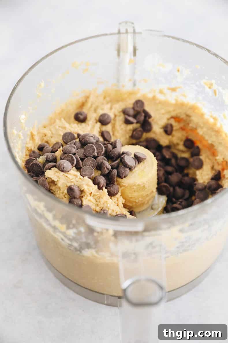 Wholesome Chickpea Blondies 6 Chocolate chips being stirred into the smooth chickpea blondie batter in a food processor bowl, ensuring even distribution.