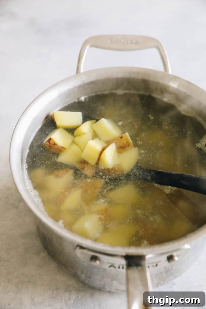 Crispy Roasted Potatoes: Two Mouthwatering Variations 2 Potatoes boiling in a pot on the stovetop.