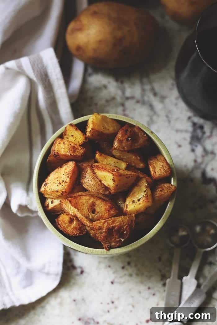 Crispy Roasted Potatoes: Two Mouthwatering Variations 8 Overhead image of crispy roasted potatoes in a vibrant green bowl, generously topped with fresh spices and herbs.