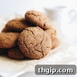 A close-up of a stack of ginger molasses cookies, with a light dusting of coconut sugar visible on their cracked surfaces.