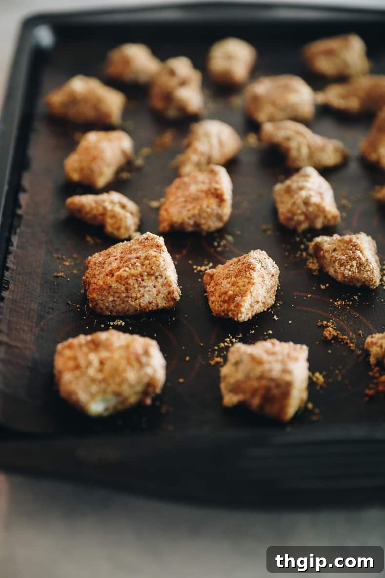 Caramelized Orange Chicken 4 Chicken bites covered in seasonings arranged on a baking sheet.