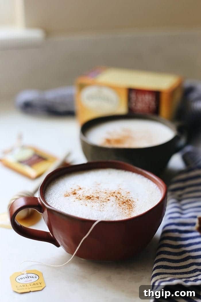 Crafting the Perfect London Fog Latte 2 A beautifully crafted London Fog drink in a clear mug, showcasing layers of dark tea and luxurious frothy milk, ready to be enjoyed on a cozy day.