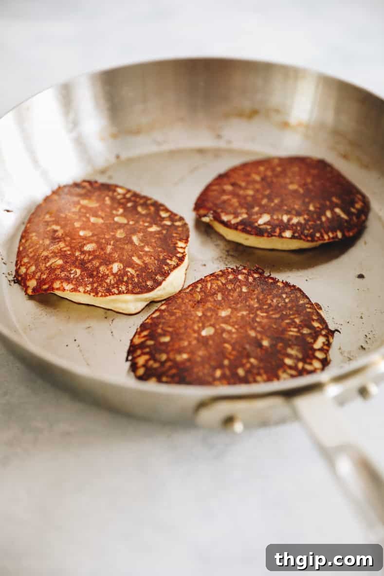 Effortless Blender Banana Oatmeal Pancakes 2 3 banana oatmeal pancakes in silver frying pan.