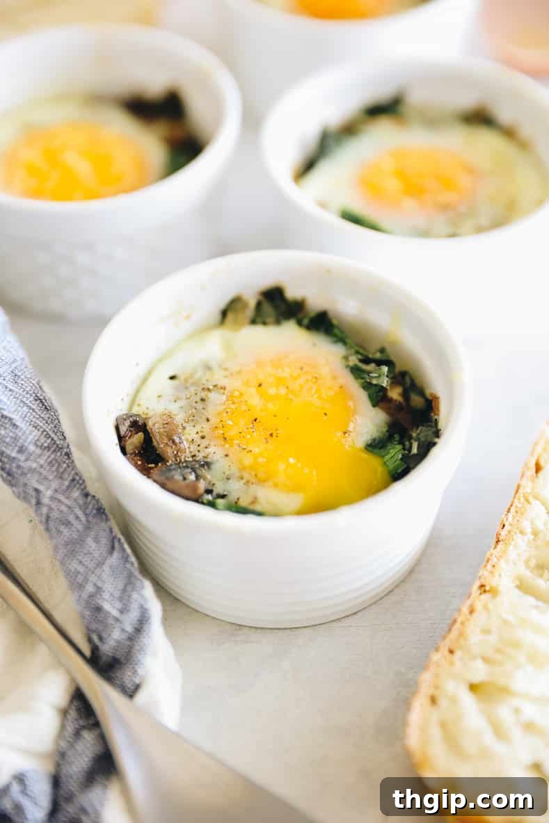 Shirred Eggs 5 Three golden-baked eggs in ramekins, nestled amidst tender vegetables, ready to be enjoyed.