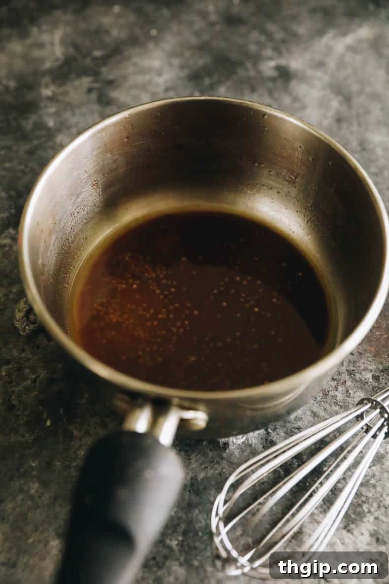 Coconut spice oil for drizzling in a small pot, showing toasted whole spices.