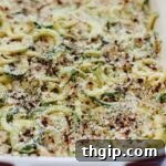 A top-down shot of the spiralized zucchini mac and cheese in a cast iron skillet, garnished with fresh herbs.