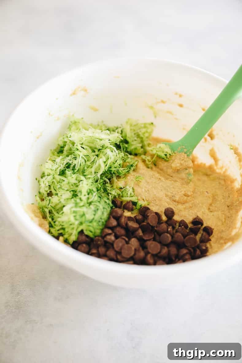 Wholesome Zucchini Banana Bread 6 Zucchini and chocolate chips being folded into the banana bread batter in a mixing bowl.