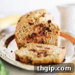 Zucchini banana bread loaf on a silver platter. Slice of bread cut away from the loaf.