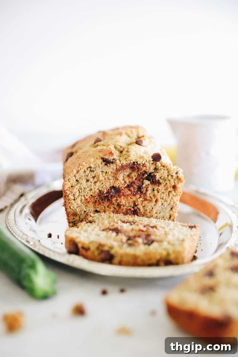 Wholesome Zucchini Banana Bread 10 Healthy zucchini bread sliced on a silver platter, showcasing its moist texture and chocolate chips.