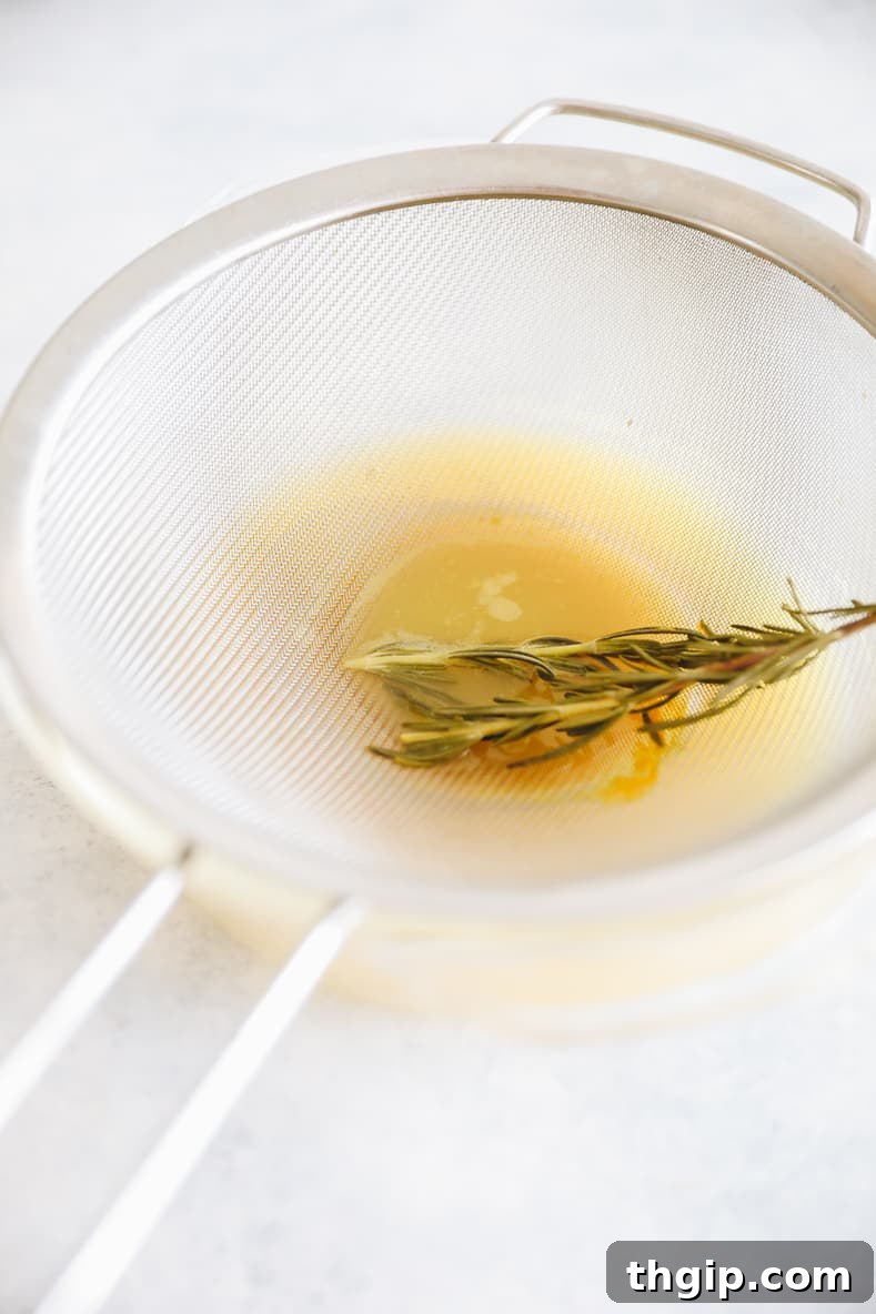 Zesty Orange Rosemary Scones 5 Straining rosemary sprigs from orange juice infusion.