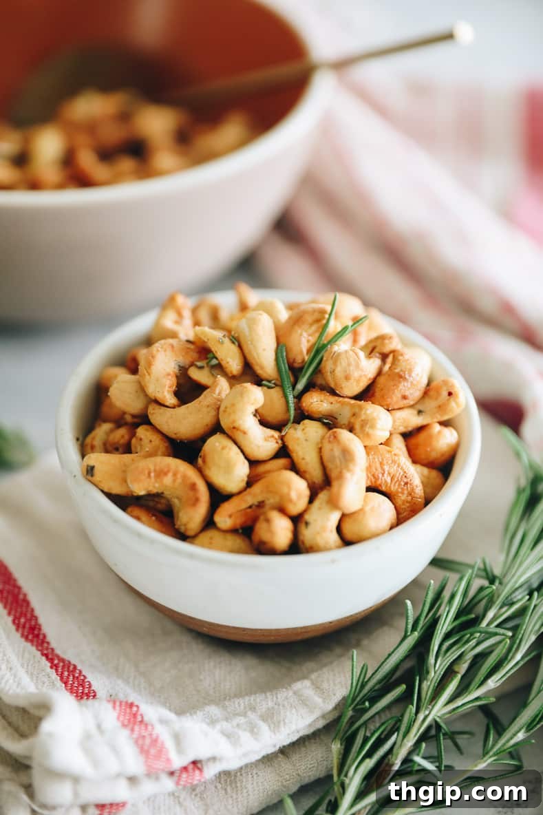 Artisan Rosemary Cashews 2 A white bowl of roasted cashews with rosemary.