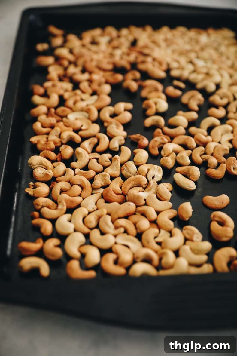 Artisan Rosemary Cashews 4 Cashews spread out on a black baking sheet.