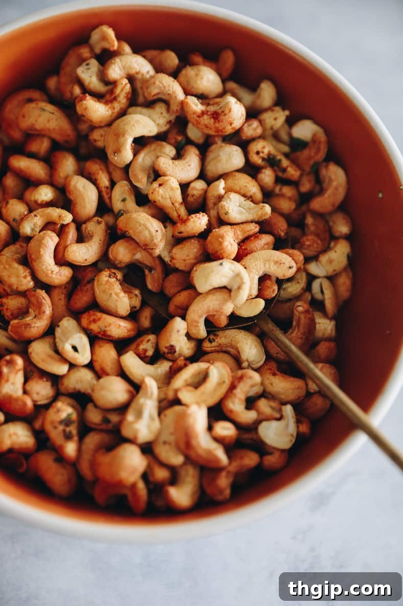 Artisan Rosemary Cashews 6 An orange bowl with spiced cashews and a gold spoon.