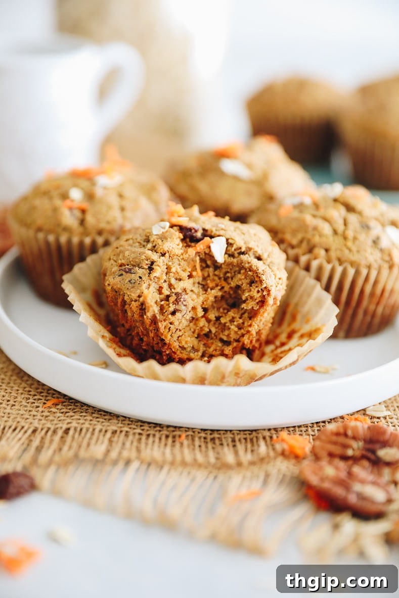 Delicious gluten-free Morning Glory Muffins on a breakfast table, one with a bite taken out.