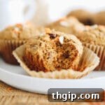 Morning glory muffins on a white platter. The muffin at the forefront has a bite taken out of it.