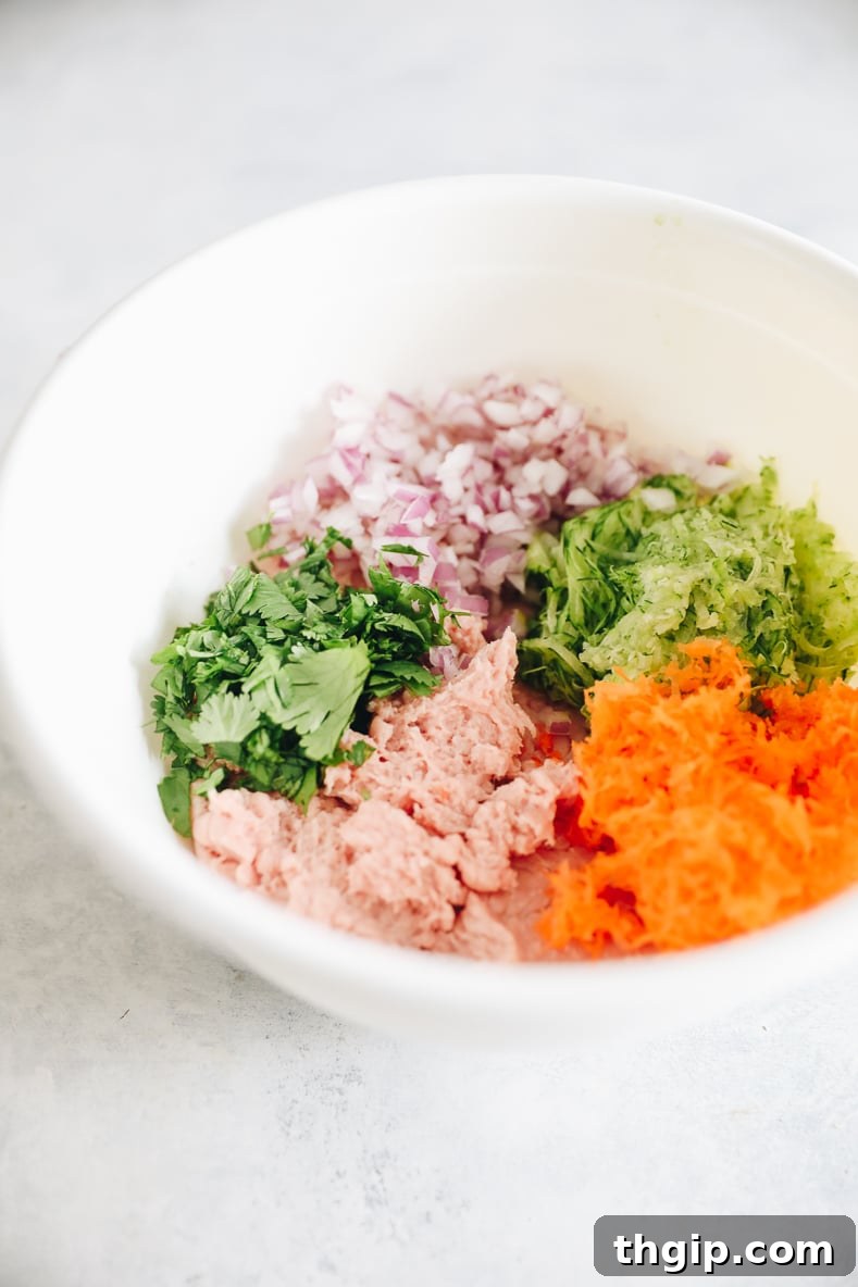 Zesty Thai Turkey Burgers with Peanut Drizzle 4 Hands forming ground turkey mixture with vegetables into uniform burger patties.