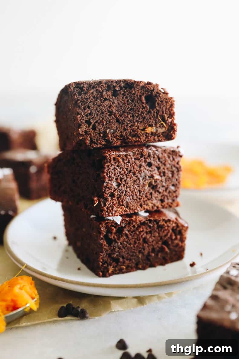 Velvety Sweet Potato Chocolate Brownies 2 Stacked fudgy sweet potato brownies on a white plate, showcasing their rich texture and deep brown color.