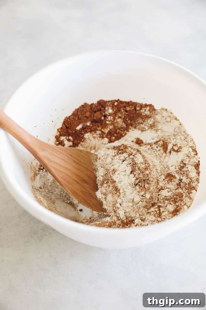 Velvety Sweet Potato Chocolate Brownies 6 Various dry ingredients for brownies, including flour, cocoa powder, sugar, and baking soda, in a white mixing bowl.