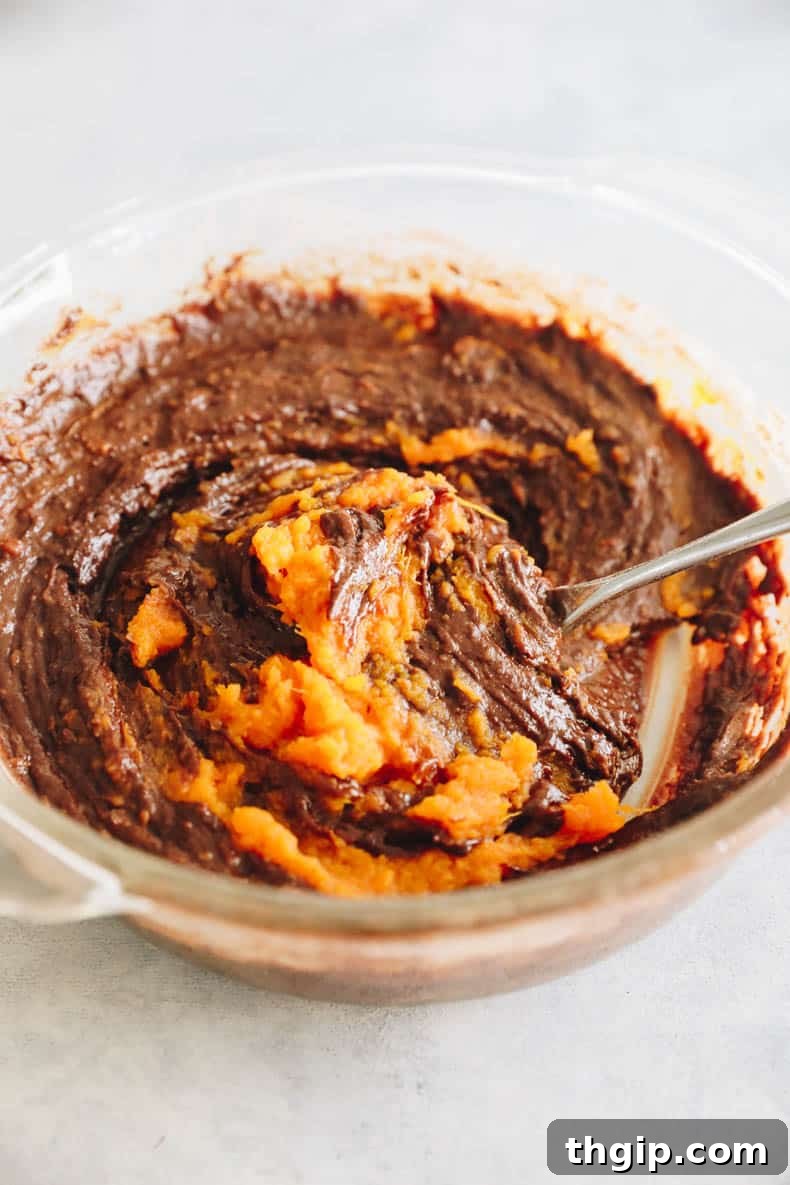 Velvety Sweet Potato Chocolate Brownies 7 Thick, glossy sweet potato brownie batter in a clear glass mixing bowl, ready for baking.