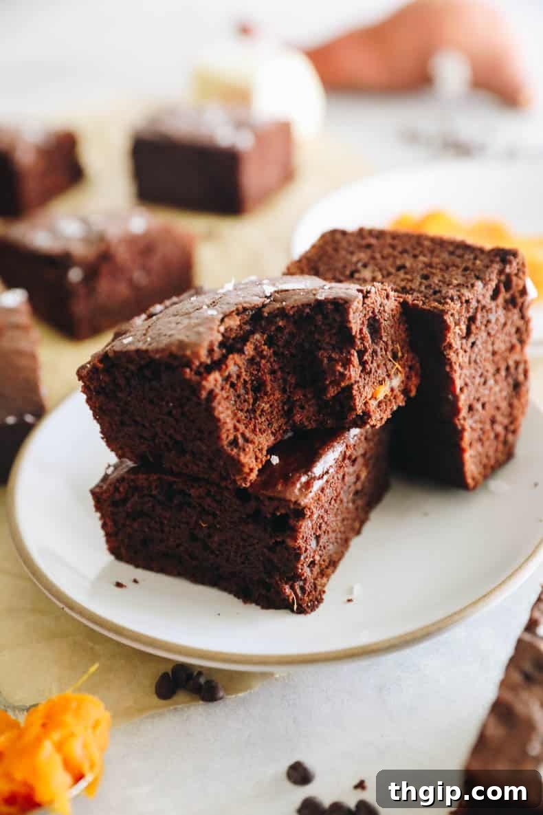 Velvety Sweet Potato Chocolate Brownies 10 Close-up of a homemade sweet potato brownie on a white plate, revealing its dense, fudgy interior and perfectly baked crust.
