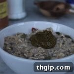 A mason jar filled with hearty overnight oats, topped with fresh fruit and seeds.