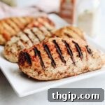 Close-up of perfectly cooked, juicy chicken breast with prominent grill marks.