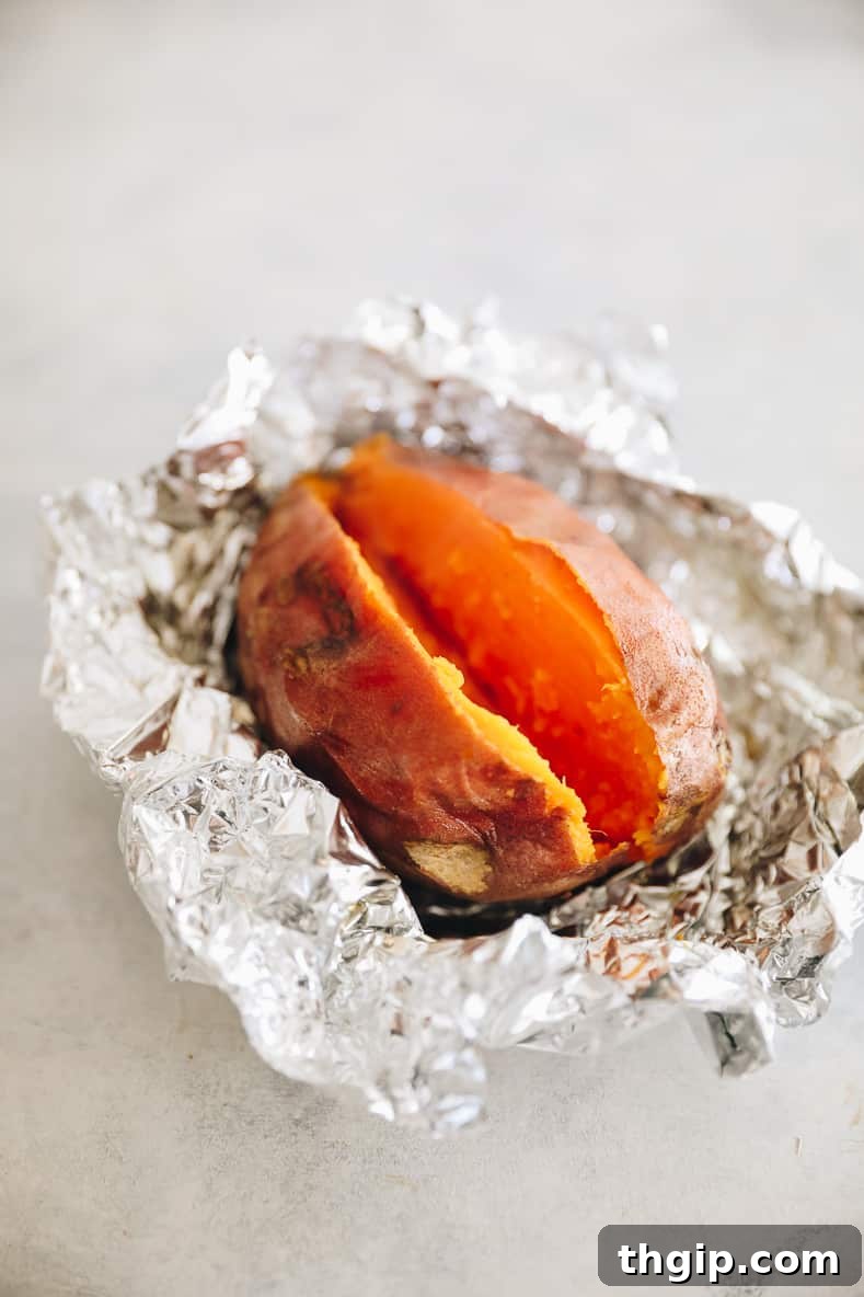 Baked sweet potato in tin foil that has been opened and sliced open.