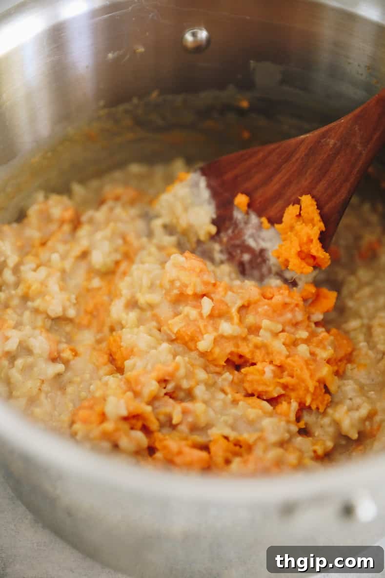Mixture of sweet potato rice pudding in pot with wooden spoon sticking out.