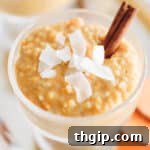 Sweet potato rice pudding in a clear serving dish with shredded coconut and a cinnamon stick on top.