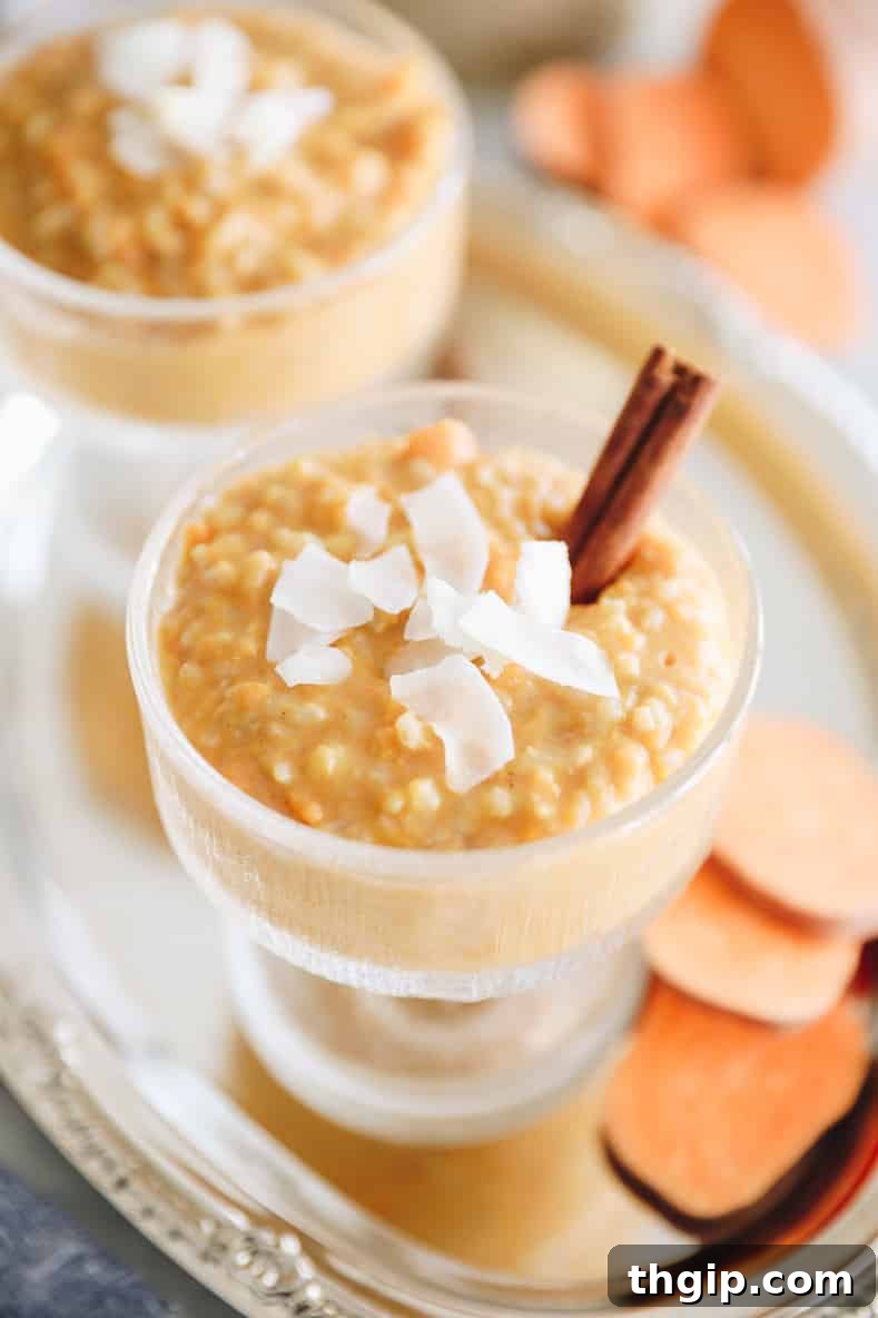 Sweet potato rice pudding in a clear serving dish with shredded coconut and a cinnamon stick on top.