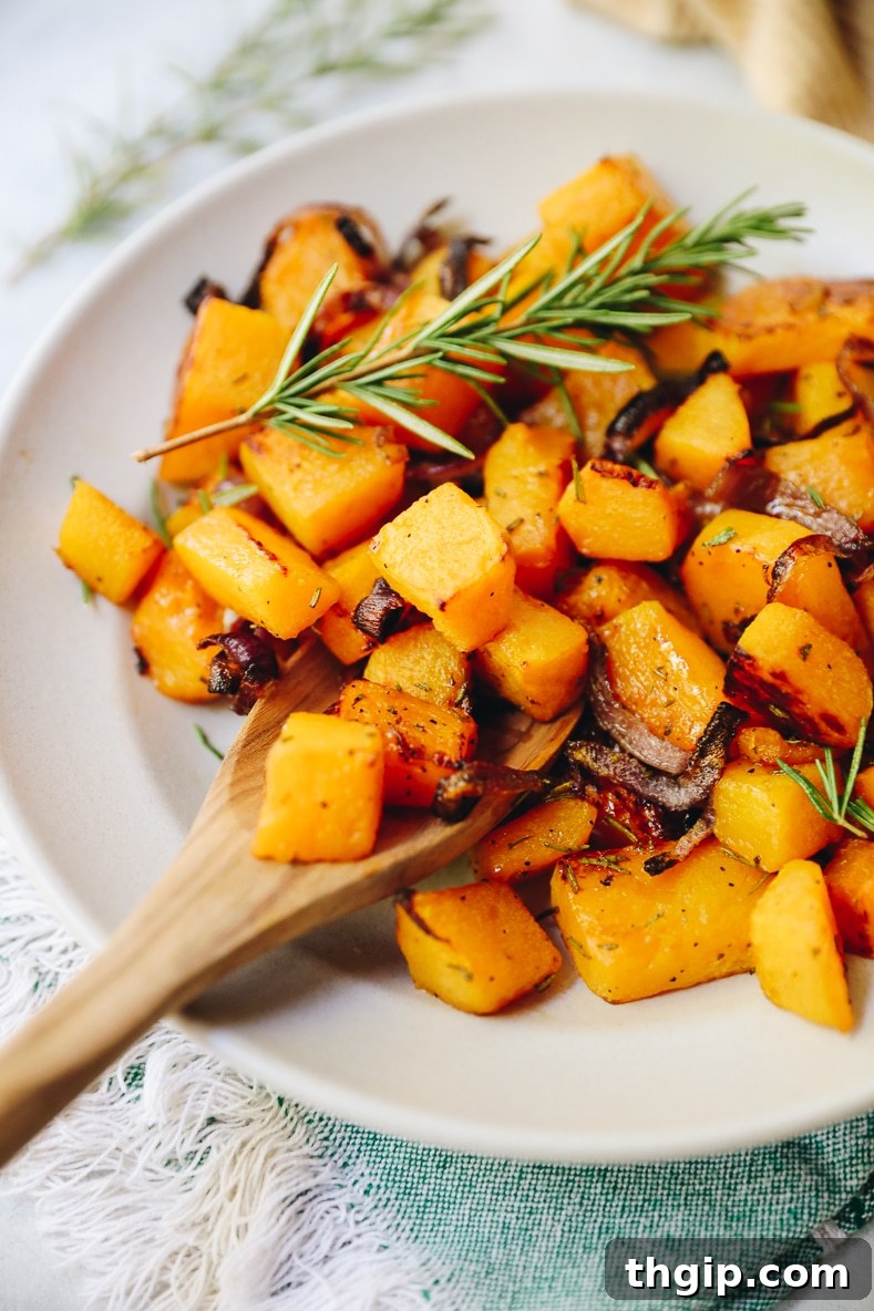 Roasted Rosemary Butternut Squash 2 Vibrant roasted rosemary butternut squash cubes in a white serving bowl, ready to be enjoyed.