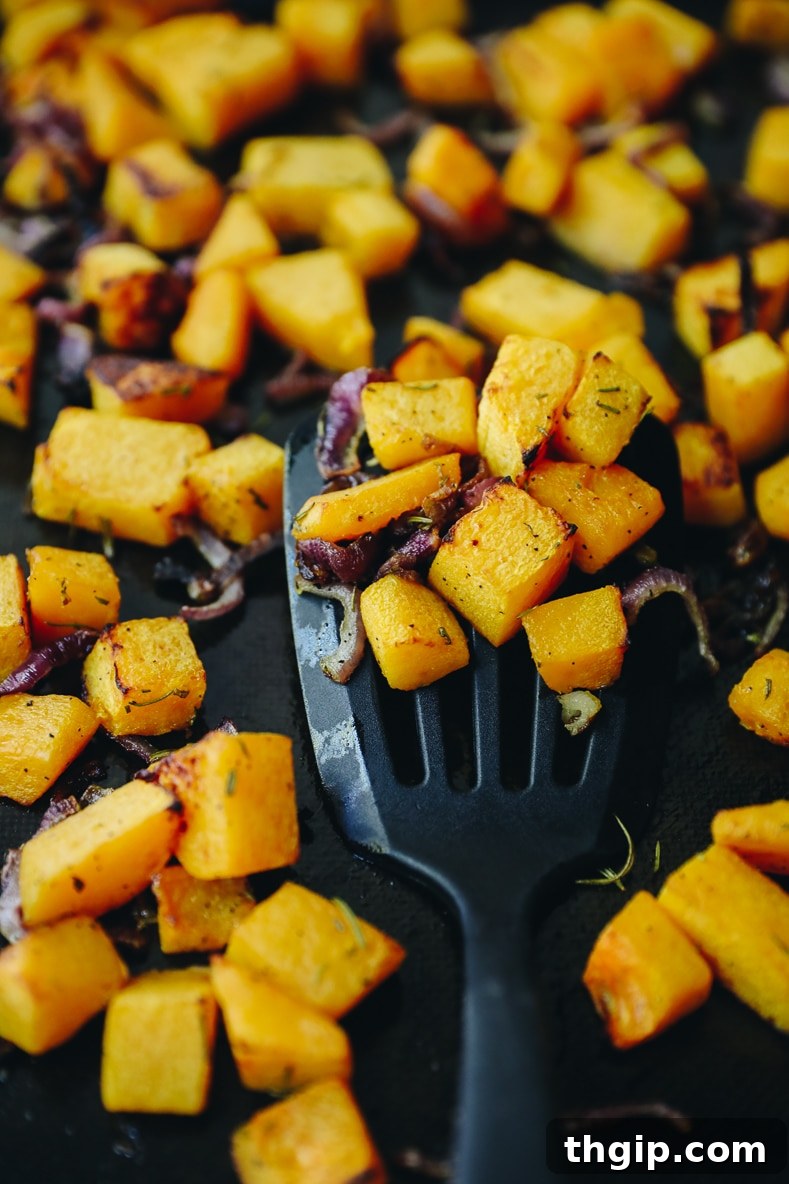 Roasted Rosemary Butternut Squash 4 Roasted butternut squash and red onion on a parchment-lined baking sheet, glistening and lightly browned.