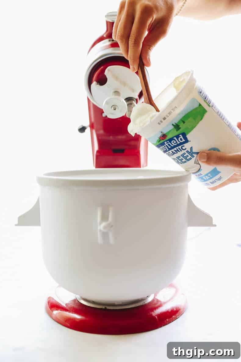 Yogurt mixture being churned in an ice cream machine to achieve creamy consistency.