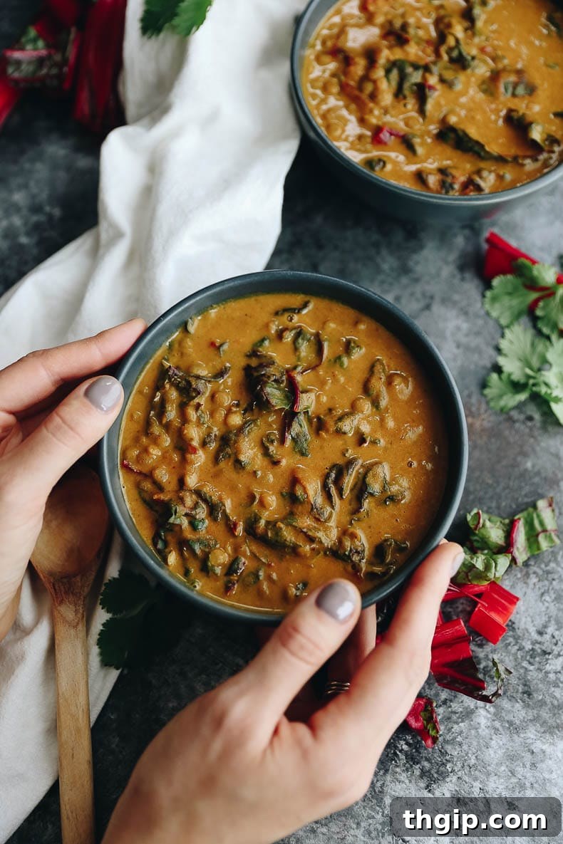 Golden Thai Lentil and Carrot Comfort Soup 2 An overhead shot of a single bowl of rich Thai curry carrot lentil soup, held by two hands, emphasizing its comforting and nourishing qualities. The texture appears creamy and inviting.