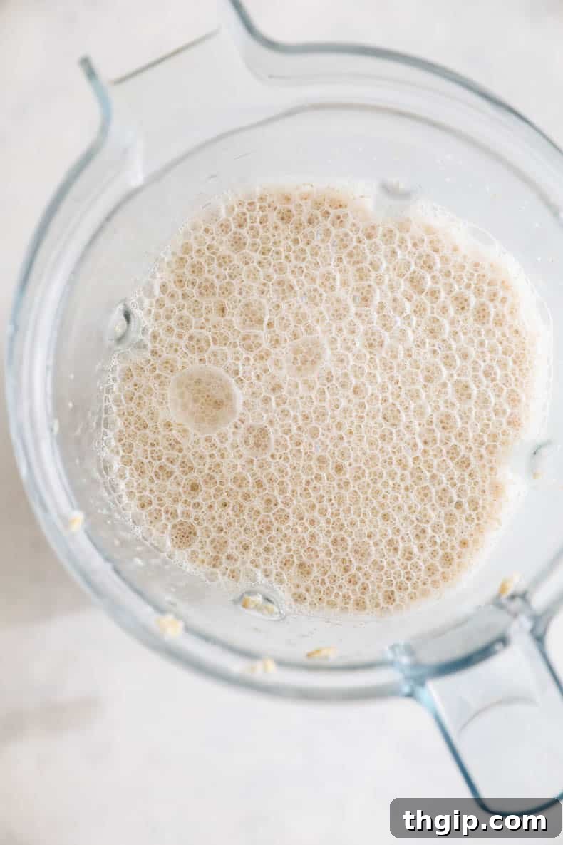 Make Your Own Oat Milk 4 Blended oats and water in a blender, ready for straining to make homemade oat milk.