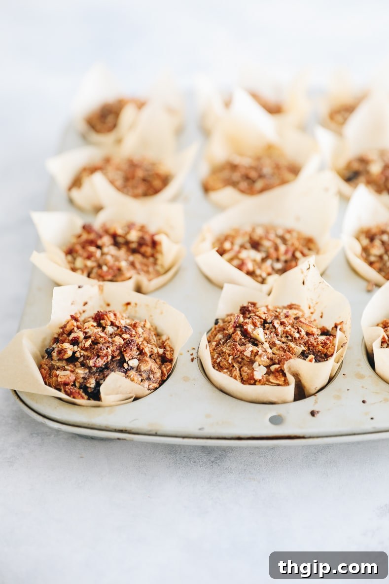 Bursting Blueberry Oat Muffins 6 Baked Blueberry Oatmeal Muffins with a crumble topping cooling in a muffin tin.