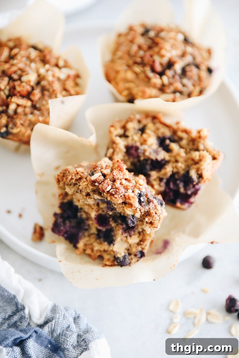 Bursting Blueberry Oat Muffins 7 A blueberry oatmeal muffin cut in half, revealing juicy blueberries and the streusel topping.