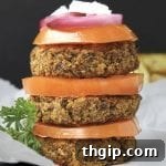 A close-up of a cooked Greek Quinoa Burger, showcasing its golden-brown crust and fresh ingredients.