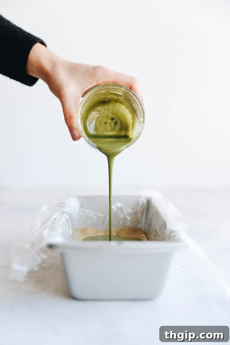 Close-up of vibrant matcha coconut butter frosting being spread onto homemade healthy and energizing vegan matcha protein bars, showcasing the beautiful green color and creamy texture.