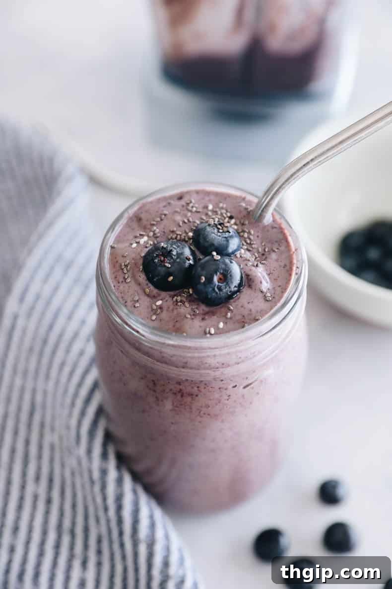 Vibrant blueberry smoothie in a mason jar, garnished with fresh blueberries and a stylish straw, ready to be enjoyed.