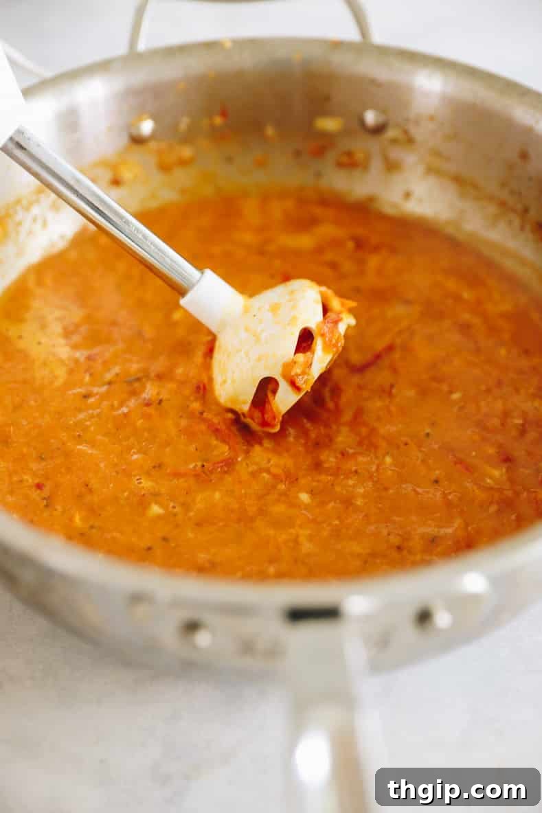 Fiery Homemade Arrabbiata 4 An immersion blender blending up spicy arrabbiata sauce in a large pot, creating a smooth texture.